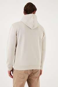 Felpa leggera color beige con tasca a marsupio, cappuccio regolabile con lacci e polsini a costine. Tessuto morbido, design semplice senza loghi o motivi visibili.