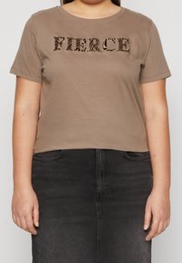 Kortärmad brun bomullströja med en texturerad grafik som visar ordet "FIERCE" i svart djurmönster mot en enfärgad bakgrund.