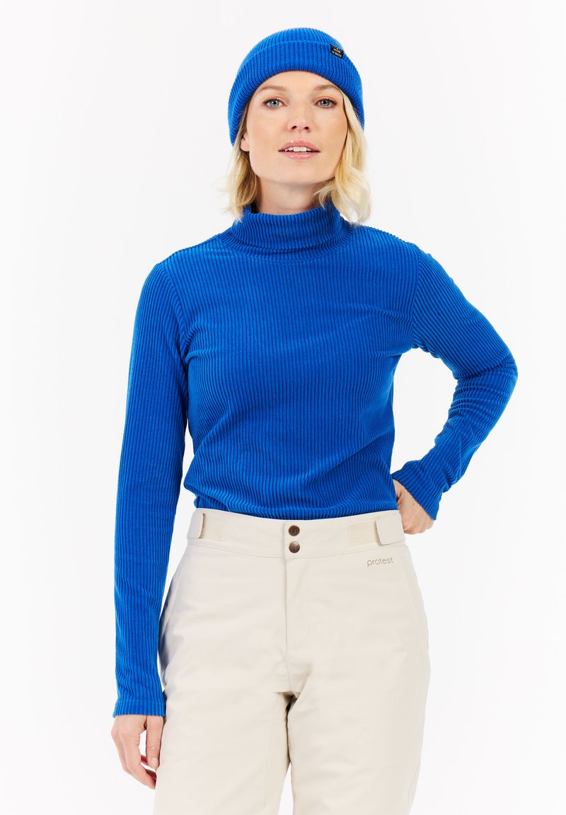 Blauer gerippter Rollkragenpullover mit langen Ärmeln, kombiniert mit cremefarbenen Hosen mit Knopfdetails und einem Markenlogo am Bund.
