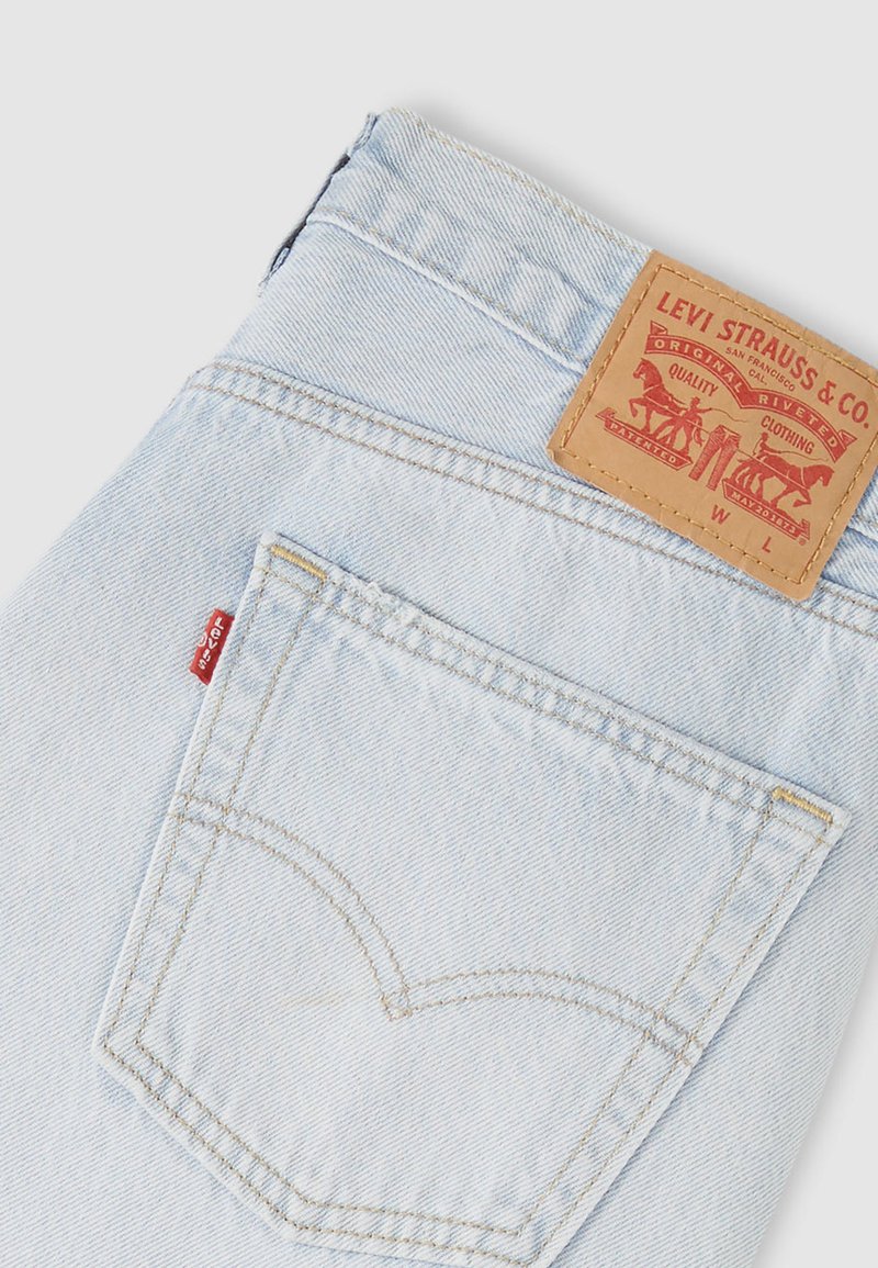 Hellblaue Jeans aus Denim mit einem beigefarbenen Lederpatch mit Logo, geschwungenem Design der Gesäßtaschen und rotem Label an der Seitennaht.
