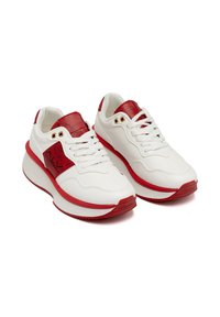 Sneaker bianchi con accenti rossi, dotati di un pannello rosso testurizzato vicino ai lacci, punta rotonda e una sola di gomma rossa spessa.