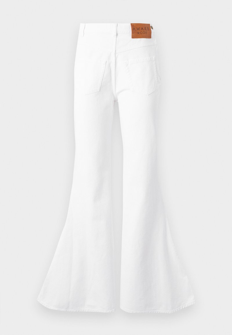 White high-waisted flared jeans with back pockets and a brown leather patch labeled "A.W.A.K.E MODE" at the waistband.