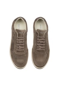 Brown suede sneakers with six eyelets, flat laces, and a low profile. Cream rubber sole contrasts with the upper material. Logo on the tongue.