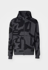 Sweat à capuche zippé gris foncé avec motifs géométriques abstraits noirs, poches avant et capuche avec cordon sur fond clair.