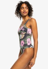 Maillot de bain une pièce vert avec des motifs floraux en rose, blanc et jaune. Doté d'une découpe latérale et de bretelles ajustables. Texture lisse.