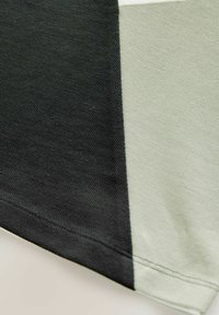 Bomuldsstof med et geometrisk design, der har sorte og lysegrå sektioner. Glat tekstur med pæne sømme langs kanterne.