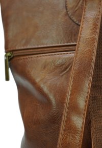 Bruine leren tas met een gestructureerde afwerking, voorzien van een centrale rits en een bijpassende band. Geaccentueerd door een glad oppervlak met glans.