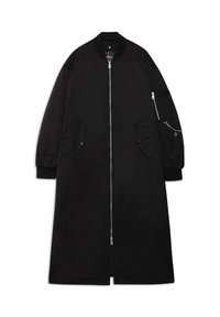 Lang sort frakke lavet af glat stof, med en forlynlås, sidelommer og en lomme med lynlås på ærmet med kædeudstyr.