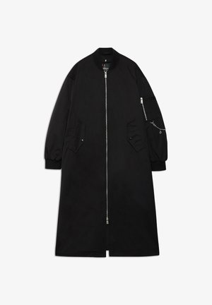 Abrigo largo negro hecho de tela suave, con cremallera frontal, bolsillos laterales y un bolsillo con cremallera en la manga con un detalle de cadena.