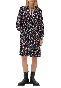 Blumenmusterkleid mit langen Ärmeln und gerafftem Ausschnitt, das eine Kordelzugbindung aufweist. Hergestellt aus leichtem Stoff in Marineblau mit bunten Akzenten.