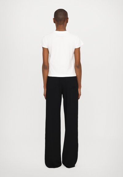 White short-sleeve t-shirt paired with high-waisted black wide-leg pants; both garments have a smooth texture and minimal design.
