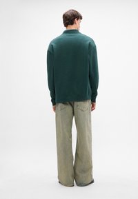 Üle mõõtme roheline särksweater pehme tekstuuriga, kantud heledate hallide laia säärega teksadega. Lihtne disain ribilise krae ja varrukaotstega.