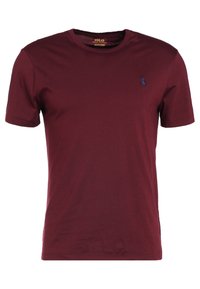 Burgundské bavlněné tričko s kulatým výstřihem, krátkými rukávy a malým modře vyšitým logem polo na hrudi.