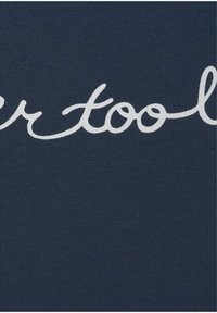 Jūros spalvos audinys su baltu kursyvu užrašu "jūsų įrankiai". Tekstūra atrodo minkšta ir šiek tiek elastinga, su lygiu paviršiumi.