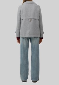 Manteau en mélange de laine gris avec un col rabattable, deux boutons et un dos légèrement court. Associé à un jean large bleu clair.