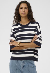 Kurzärmliges T-Shirt mit marineblauen und weißen Streifen aus weichem Material, mit lässiger Passform und Rundhalsausschnitt, kombiniert mit hellblauer Denim.