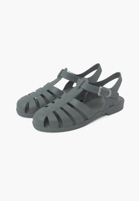 Green rubber sandals with open-toe design, interwoven straps, adjustable ankle buckle, flat sole, and textured surface.