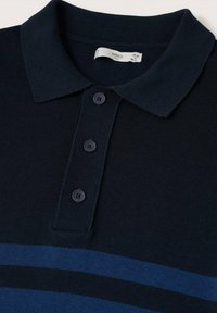 Camisa polo azul marino con textura acanalada, rayas azules en contraste, cuello doblado y tres botones en la parte frontal. Etiqueta visible dentro del cuello.