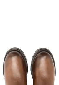 Brązowe skórzane buty z gładkim, błyszczącym wykończeniem i zaokrąglonymi palcami, z teksturowaną czarną podeszwą i ozdobnym przeszyciem wokół krawędzi.