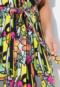 Abito colorato caratterizzato da un vivace motivo astratto di fiori e forme nei toni di rosa, giallo, verde e nero, con un dettaglio in vita legato.
