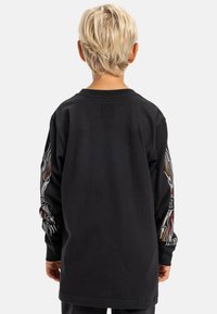 Zwarte t-shirt met lange mouwen, voorzien van kleurrijke vlamontwerpen op de mouwen, gemaakt van zacht katoenen materiaal met een relaxte pasvorm.
