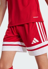 Rotes Sportshirt und kurze Hose aus leichtem Material. Die Shorts haben weiße Streifen und ein weißes Adidas-Logo auf der rechten Seite.