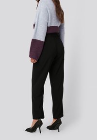 Hedvábný svetr v modro-fialové kombinaci, spárovaný s černými kalhotami a texturovanými černými podpatky; měkká látka, volný střih, dlouhé rukávy.