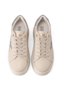 Beżowe skórzane trampki z błyszczącymi szarymi akcentami, płaskimi sznurowadłami, wyściełanym kołnierzem i jasną gumową podeszwą. Logo marki na języku.