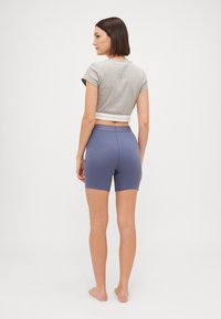 Pelēks īsais krekliņš ar baltu apdari un ziliem ribotajiem šortiem. Apģērbs ir ar pieguļošu dizainu un gludām tekstūrām.