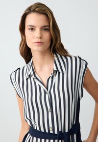 Hemdblusenkleid mit vertikalen Marine- und weißen Streifen, kurzen Ärmeln und einem taillierten Gürtel sowie einer glatten Textur.