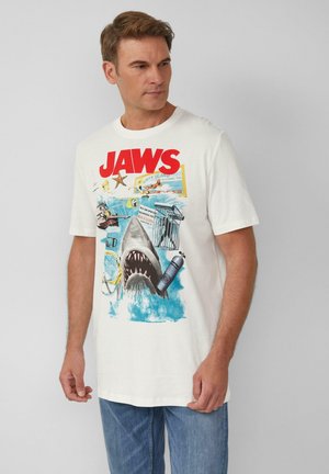 Weißes Baumwoll-T-Shirt mit einem Grafikdesign eines Hais, umgeben von blauen Wellen und mehrfarbigem Text "JAWS" sowie Vintage-Elementen.