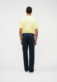 Marineblå cordfløyel bukser med rett ben-design, kombinert med en lys gul bomull t-skjorte. Baksiden har to lommer og en liten logo.