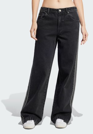 Svarta vida jeans i denim, med hög midja, framfickor och sidostripes. Bärs med vita sneakers.