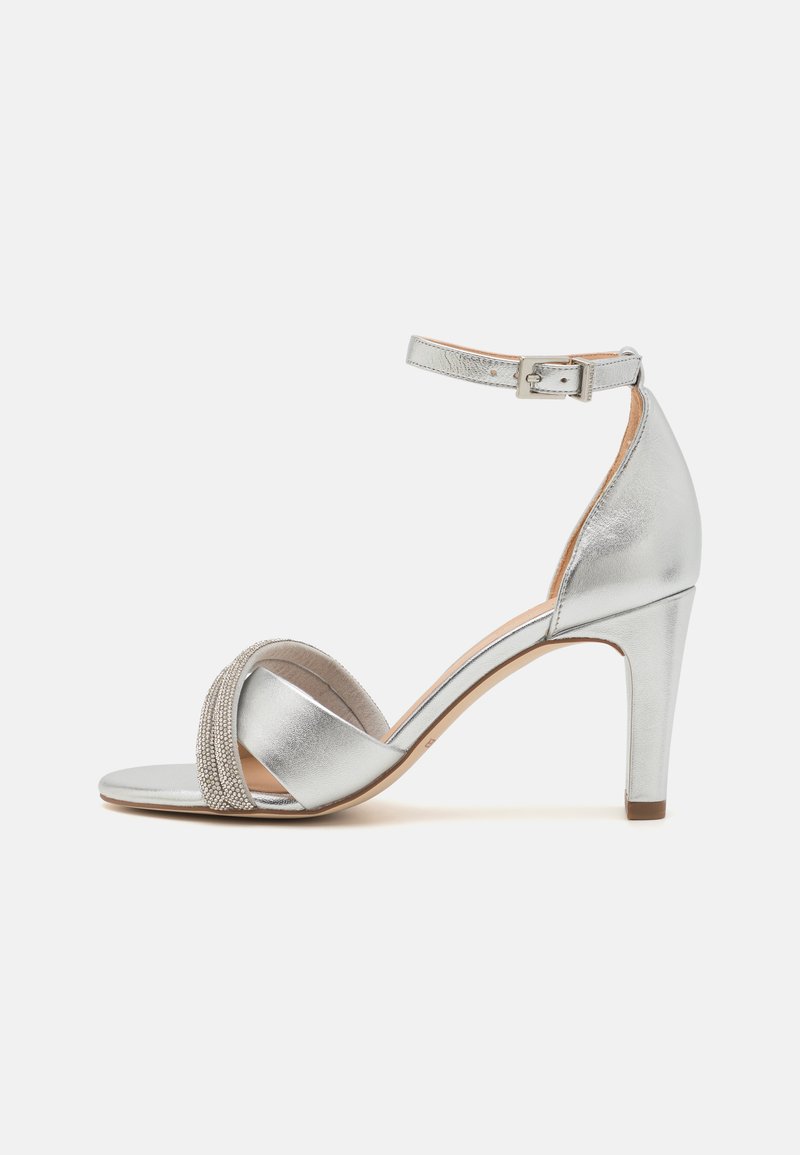 Silberne High-Heel-Sandalen mit Knöchelriemen. Glatte, metallische Oberfläche, breiter Vorderband mit strukturierten Details, spitze Zehen und schlanker Absatz.
