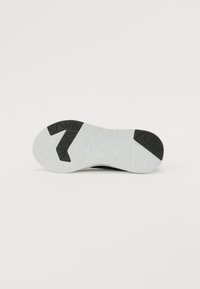 Semelle de chaussure de sport en caoutchouc noir avec une couche texturée blanche ; présente des motifs de semelle géométriques pour une adhérence et une stabilité accrues.