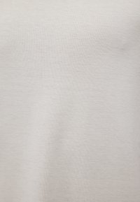 Hellgrauer Stoff mit glatter Oberfläche; weist ein einfaches, einheitliches Muster auf. Das Material wirkt weich und dehnbar, ideal für Freizeitkleidung.