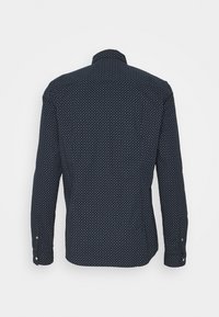 Námořnická modrá košile s dlouhým rukávem, která má malý bílý geometrický vzor, knoflíkové manžety a polo-strukturovaný límec. Hladká textilie.