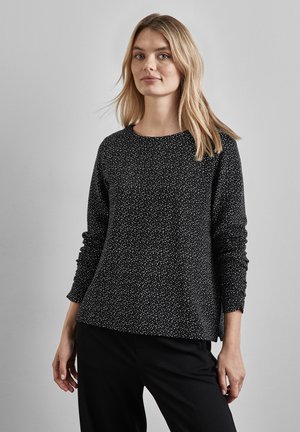 Pull noir à manches longues avec motif tacheté blanc, encolure ronde et coupe décontractée. Texture douce et fentes latérales à l'ourlet.