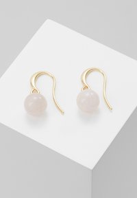 Auksinės spurgos formos auskarai su lygia, sferine šviesiai rožine akmens detalė. Dizainas minimalus, su išlenktu kabliuku ir perliuko detale.