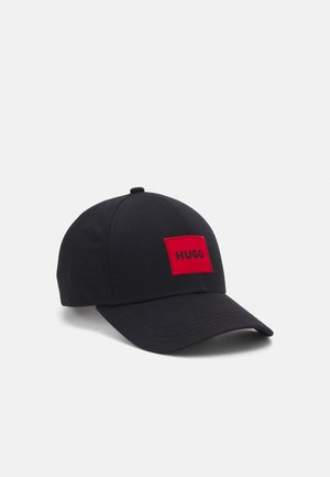 Black baseball cap with a curved brim and a red rectangular patch reading "HUGO" on the front.