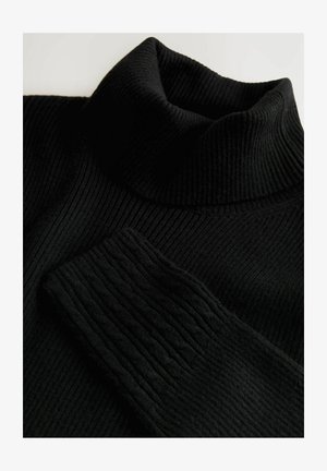 Crni rebrasti pleteni pulover s visokim ovratnikom, s preklopljenim ovratnikom i jednim rukavom koji prikazuje detaljan uzorak kabelnog pletenja.
