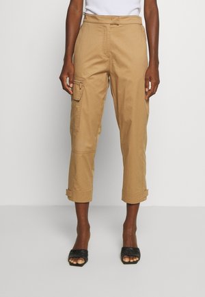 Tan cargo broek met opgerolde boorden en zijzak, gemaakt van katoen, met een relaxte pasvorm en een gladde textuur. Gecombineerd met zwarte slidesandalen.