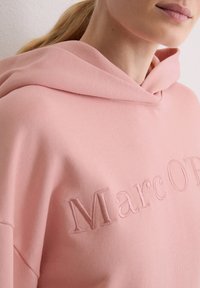 Różowa bluza z kapturem o miękkiej fakturze, z wyhaftowaną nazwą marki 'Marc O'P'. Ma luźny krój i duży kaptur.