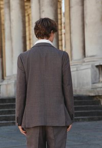 Brown checked blazer with a smooth texture, featuring a notched collar and button accents, paired with matching tailored trousers.
