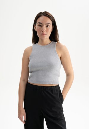 Grijze geribbelde crop top met een hoge halslijn en mouwloos ontwerp, gecombineerd met zwarte losse broek die een ontspannen pasvorm toont.