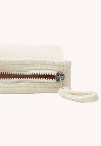 Bolsa crema texturizada con cremallera suave, forma rectangular y una correa para la muñeca. Tela suave añade detalle táctil.