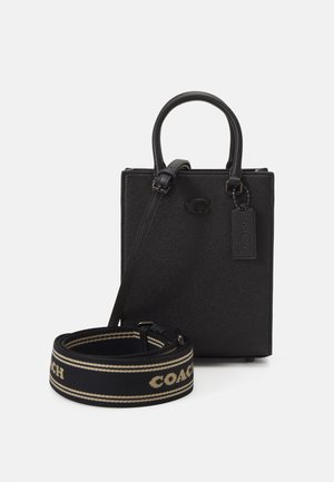 Borsa a mano in pelle nera con design strutturato, dotata di doppi manici, tracolla regolabile e una tracolla con marchio e dettagli dorati.