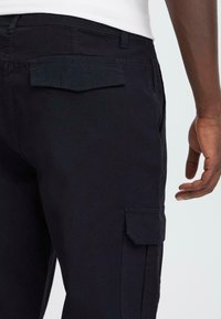 Dark blue cargo pants with a flat back pocket and side cargo pocket. Made from a durable fabric with a smooth texture.