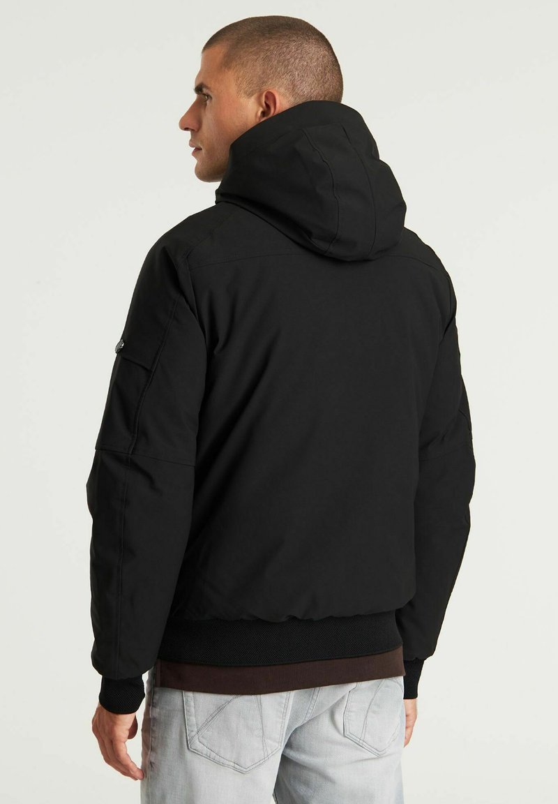 Czarna kurtka z kapturem, z zamkiem z przodu, elastycznymi mankietami i dwoma bocznymi kieszeniami. Teksturowana tkanina z gładkim wykończeniem.