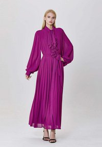 Robe longue violette en tissu fluide, dotée d'un col volanté, d'une jupe plissée, de manches longues et d'une taille cintrée.
